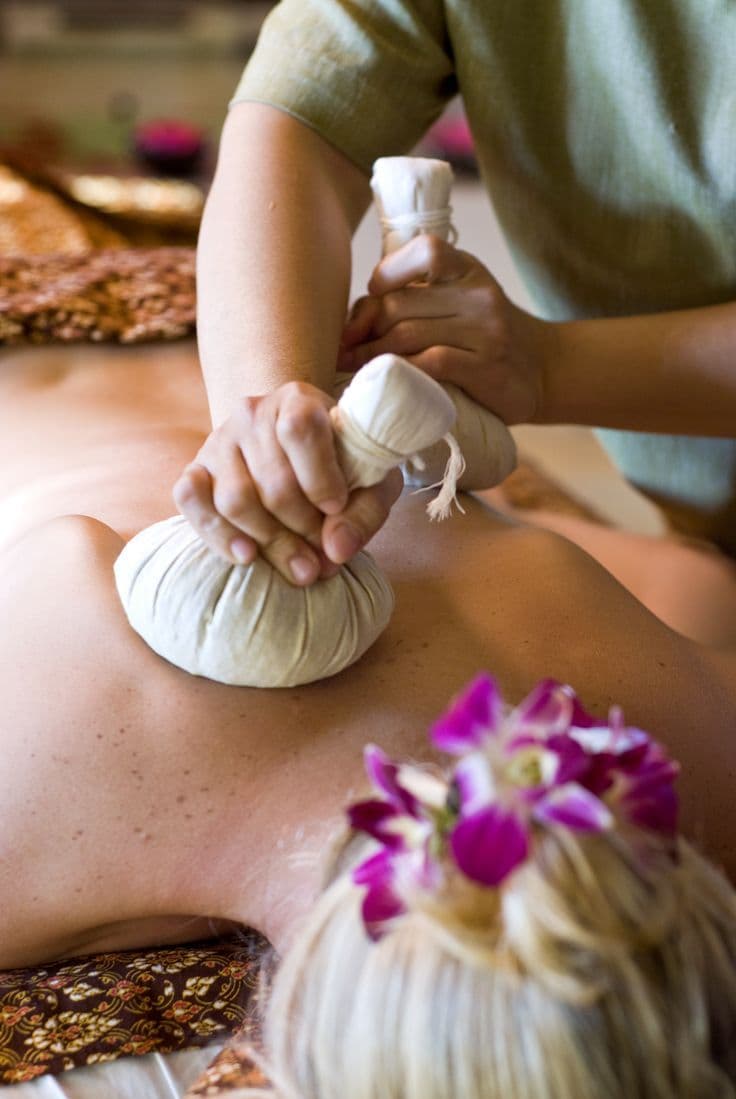 Traditional Thai therapist applying hot herbal compress